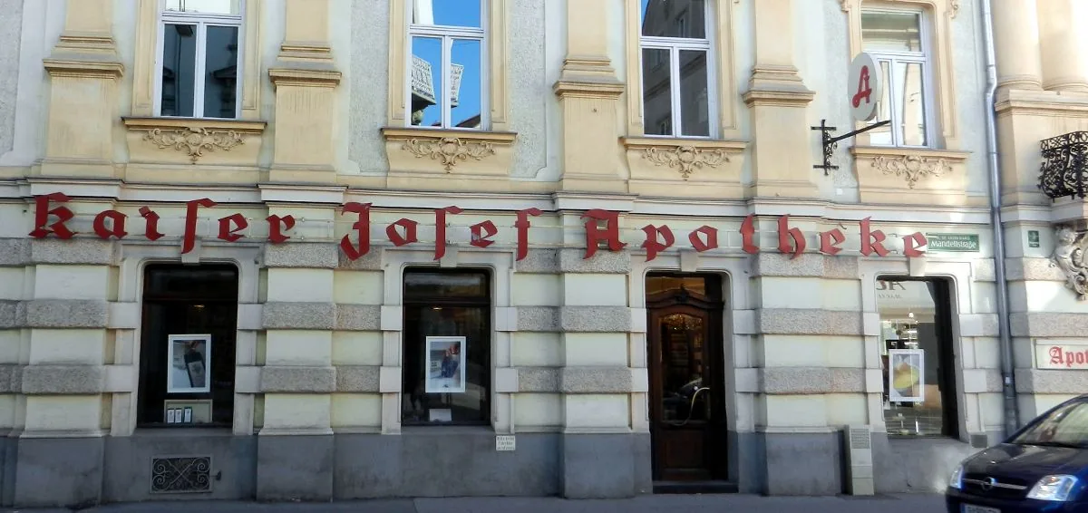 Roter Schriftzug Kaiser Josef Apotheke und Apotheken-A über den Schaufenstern der Apotheke in Graz